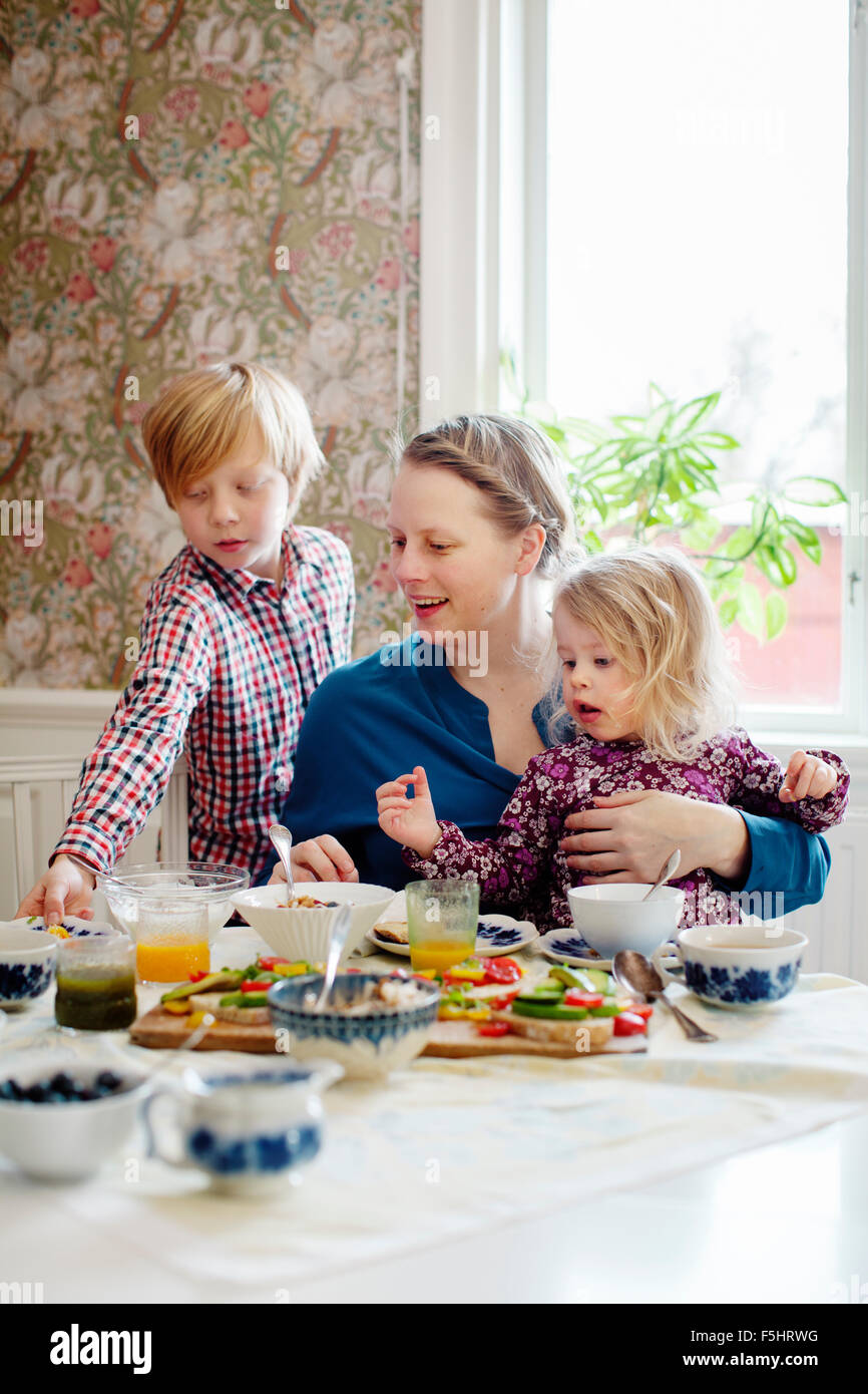 Sweden, Mother with two children (2-3, 10-11) eating breakfast Stock Photo
