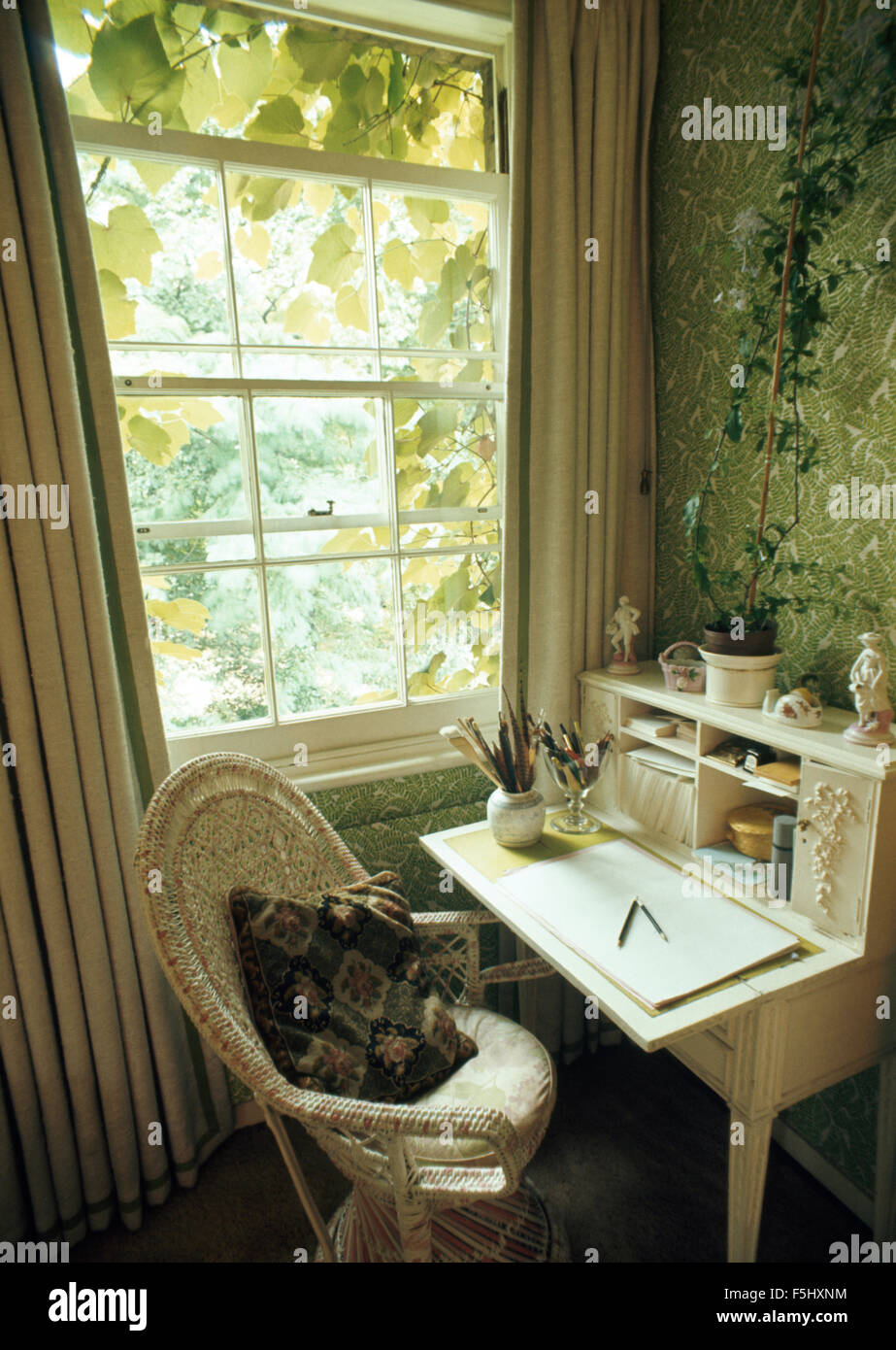 White cane chair and painted desk beside window in small sixties study