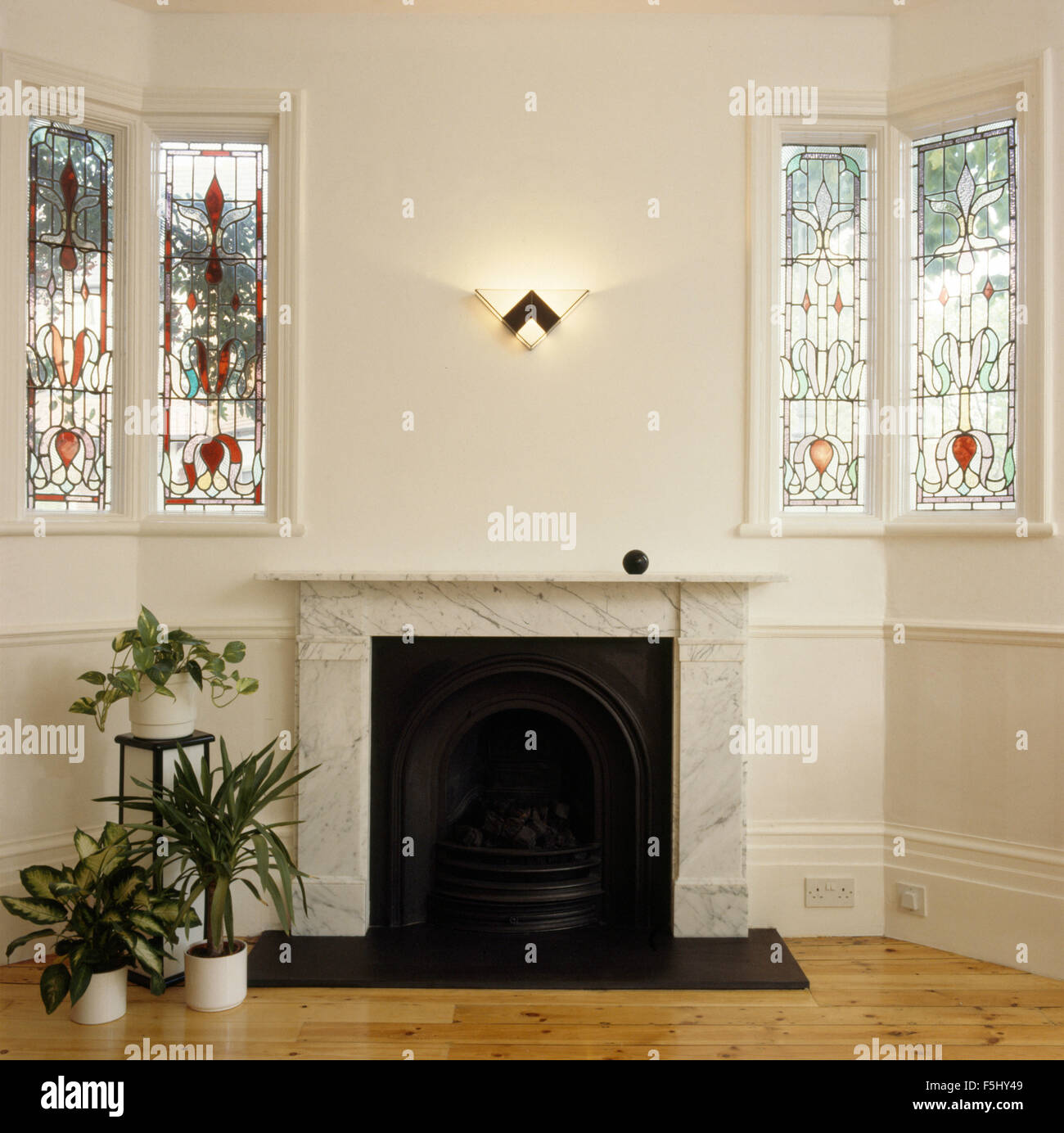 Stained glass windows either side of marble fireplace Stock Photo