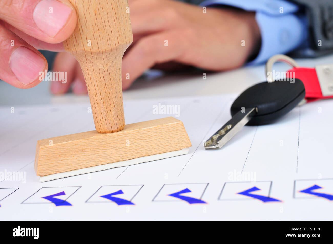 closeup of a young caucasian man in his office with a rubber stamp and a car key on his desk Stock Photo