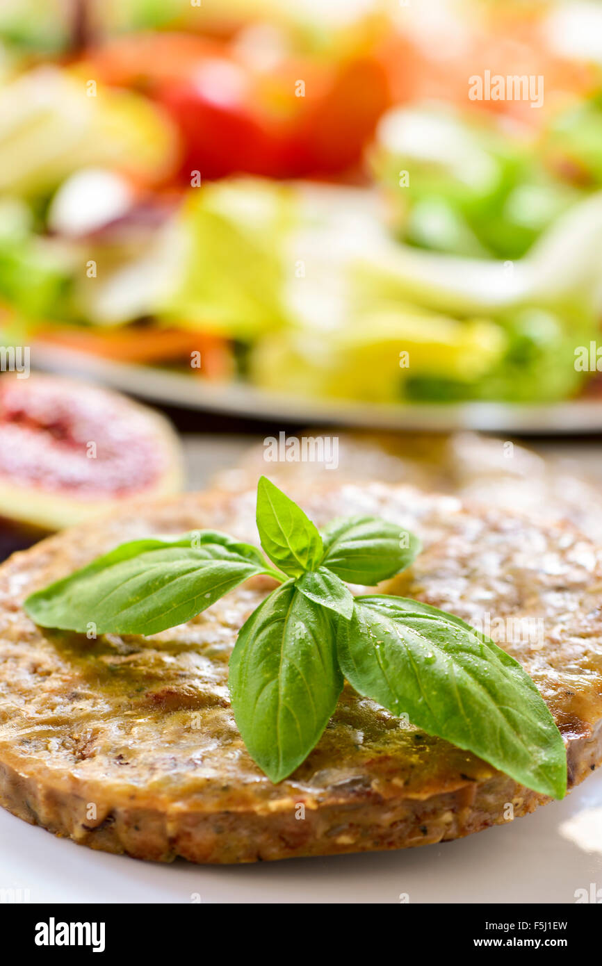 closeup of a veggie burger in a plate and a plate with salad in the background Stock Photo