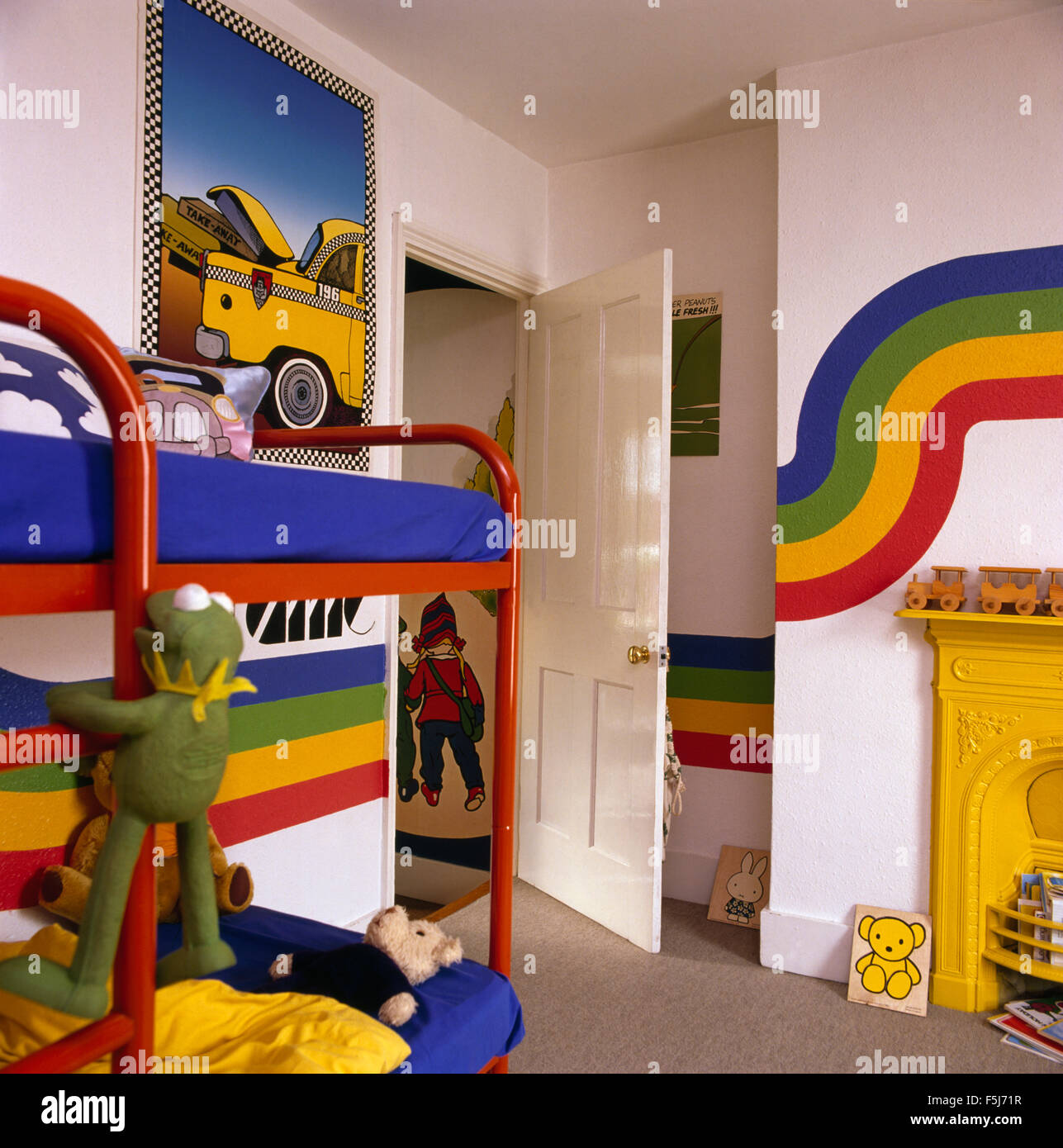 Rainbow stripes painted on walls of a children's colorful seventies bedroom with red metal bunk beds Stock Photo