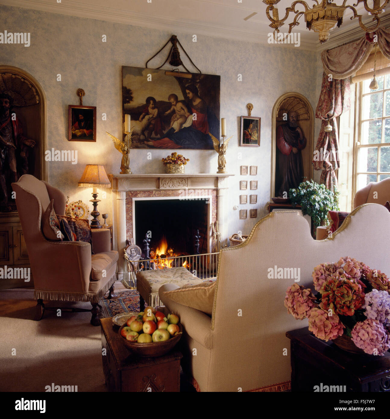 Painting above fireplace with lighted fire in opulent eighties living