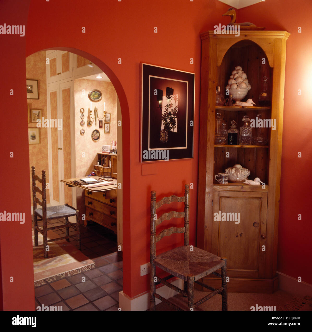 Pine corner shelf unit in red eighties hall with arched doorway to