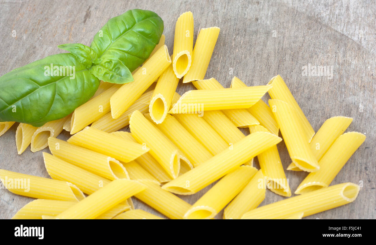 Fine penne noodles on wooden board Stock Photo