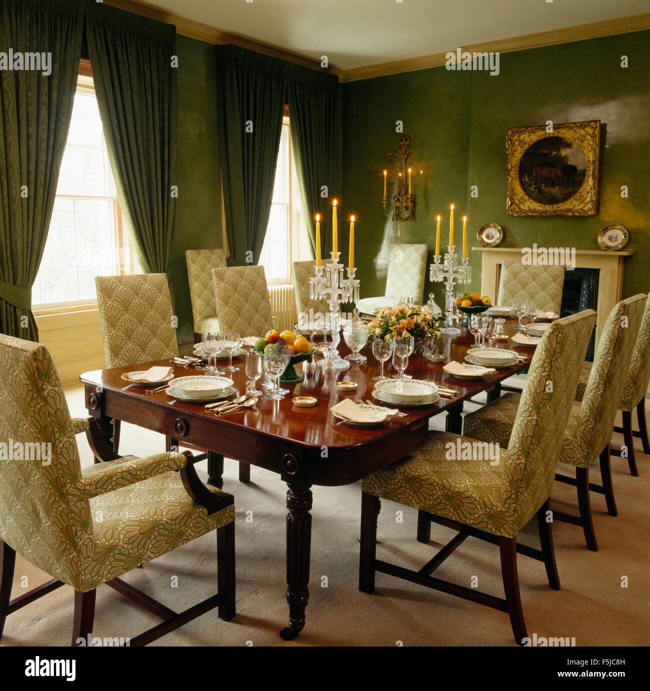 Upholstered pale green chairs at an antique table set for lunch with glass candelabra in a green eighties dining room Stock Photo Alamy