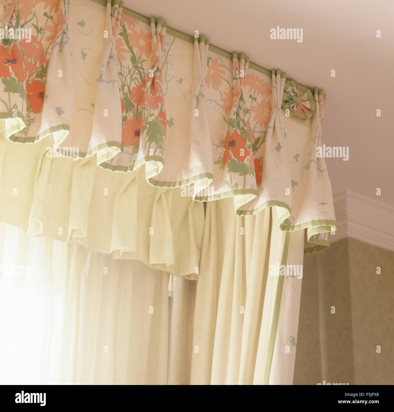 Floral pelmet and white drapes on window in eighties bedroom Stock Photo