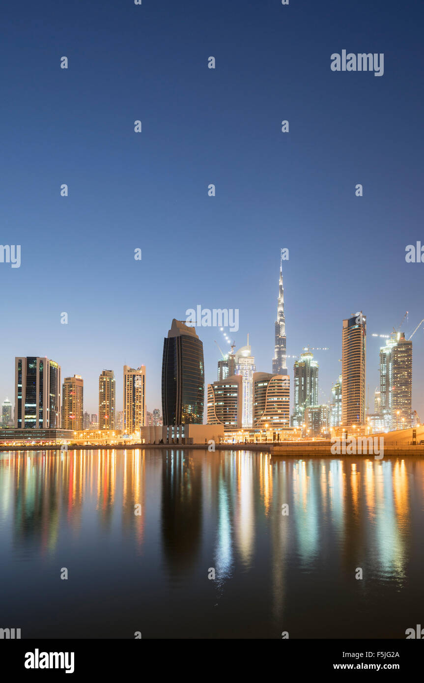 Skyline of towers reflected in the Creek at dusk in Business Bay  in Dubai United Arab Emirates Stock Photo