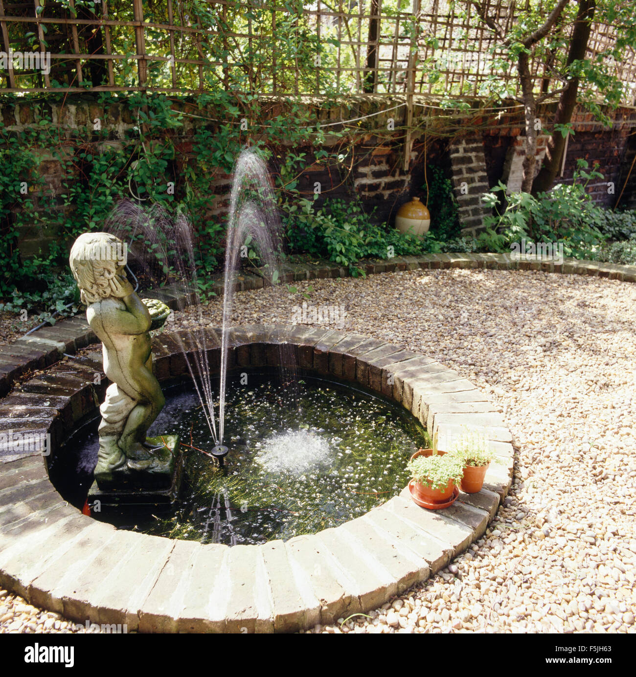 Stone statue of a boy in small circular pool with a fountain in a town