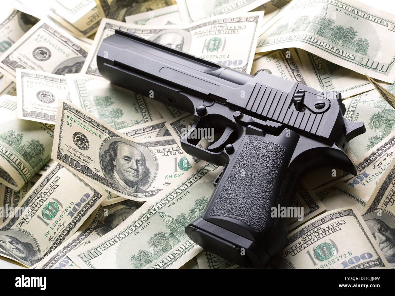 Heap of $100 dollar bills and handgun Stock Photo