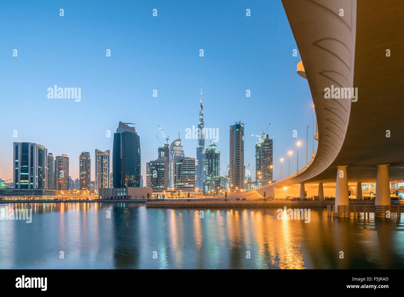 Skyline of towers at dusk in Business Bay next to bridge across the Creek in Dubai United Arab Emirates Stock Photo
