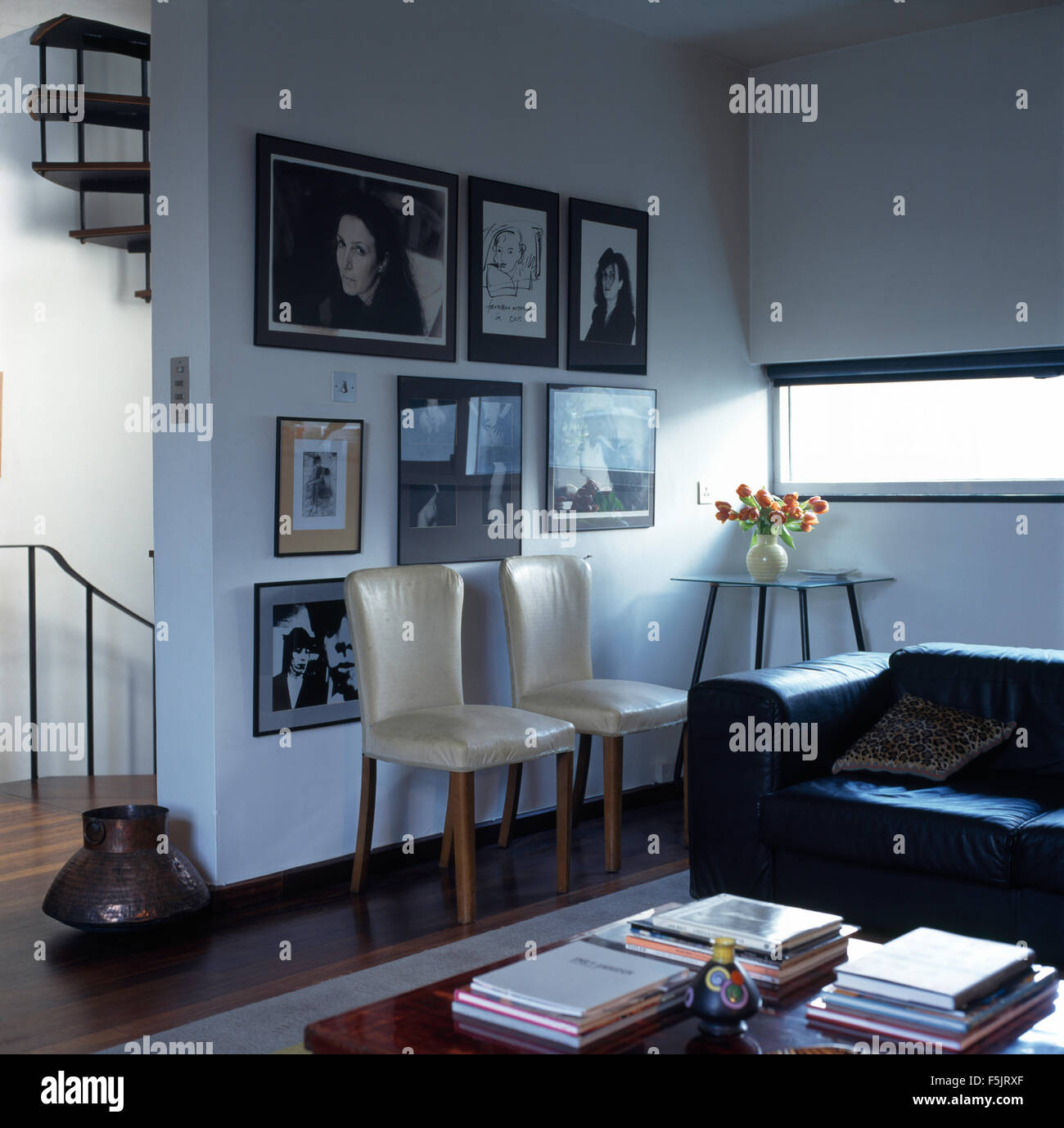 Cream leather chairs and black leather sofa in a townhouse living room with group of framed black+white photographs on the wall Stock Photo