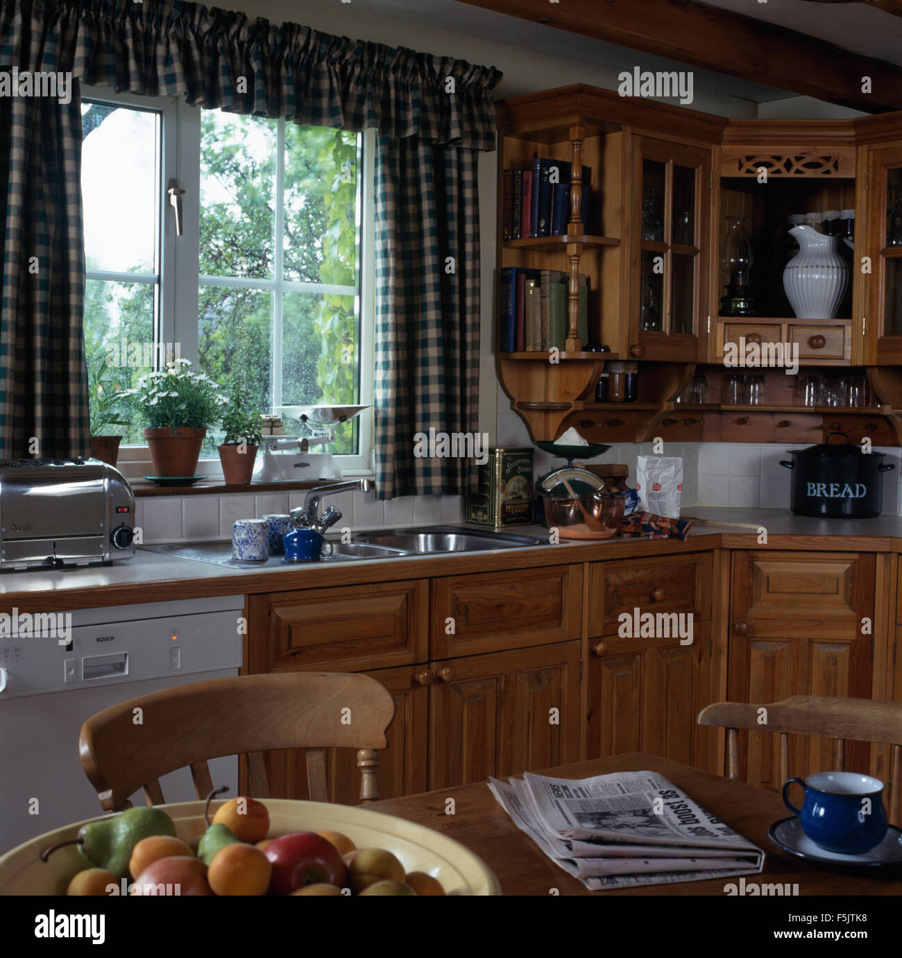 Blue Checked Curtains On Window Above Sink And Fitted Dishwasher In A Cottage Kitchen With Pine Fitted Units Stock Photo Alamy