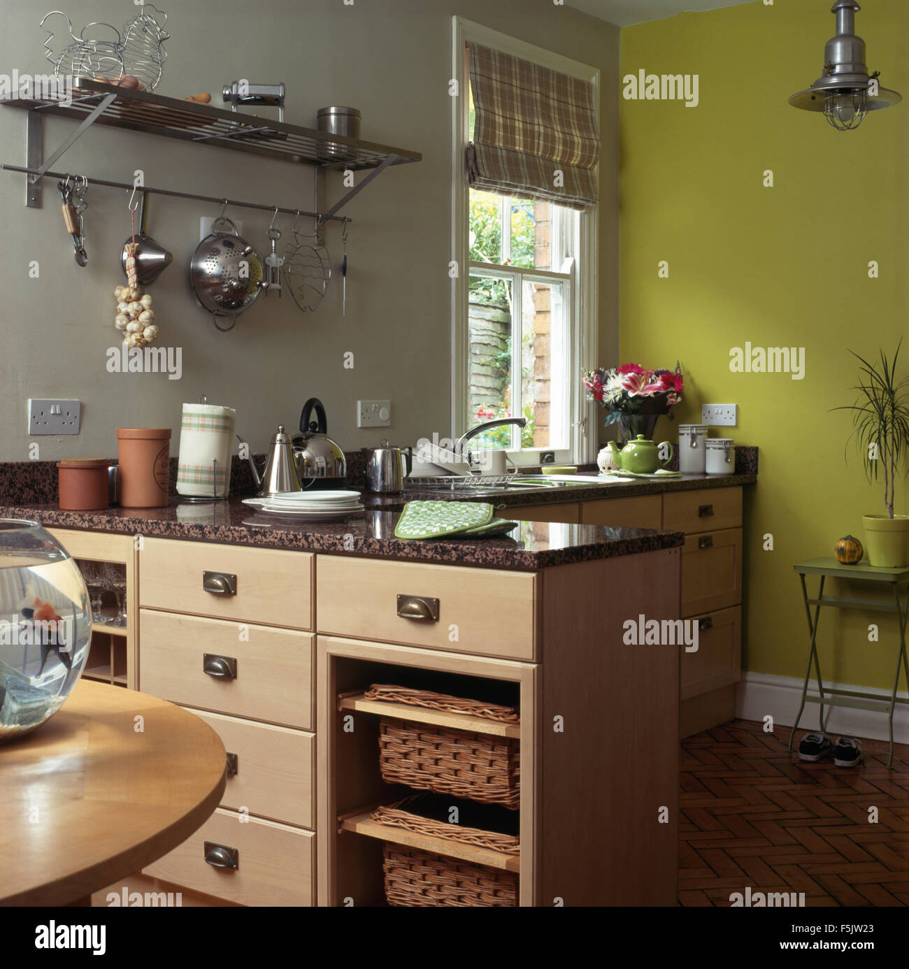 Storage baskets on shelves in peninsular unit in a lime green and gray kitchen Stock Photo