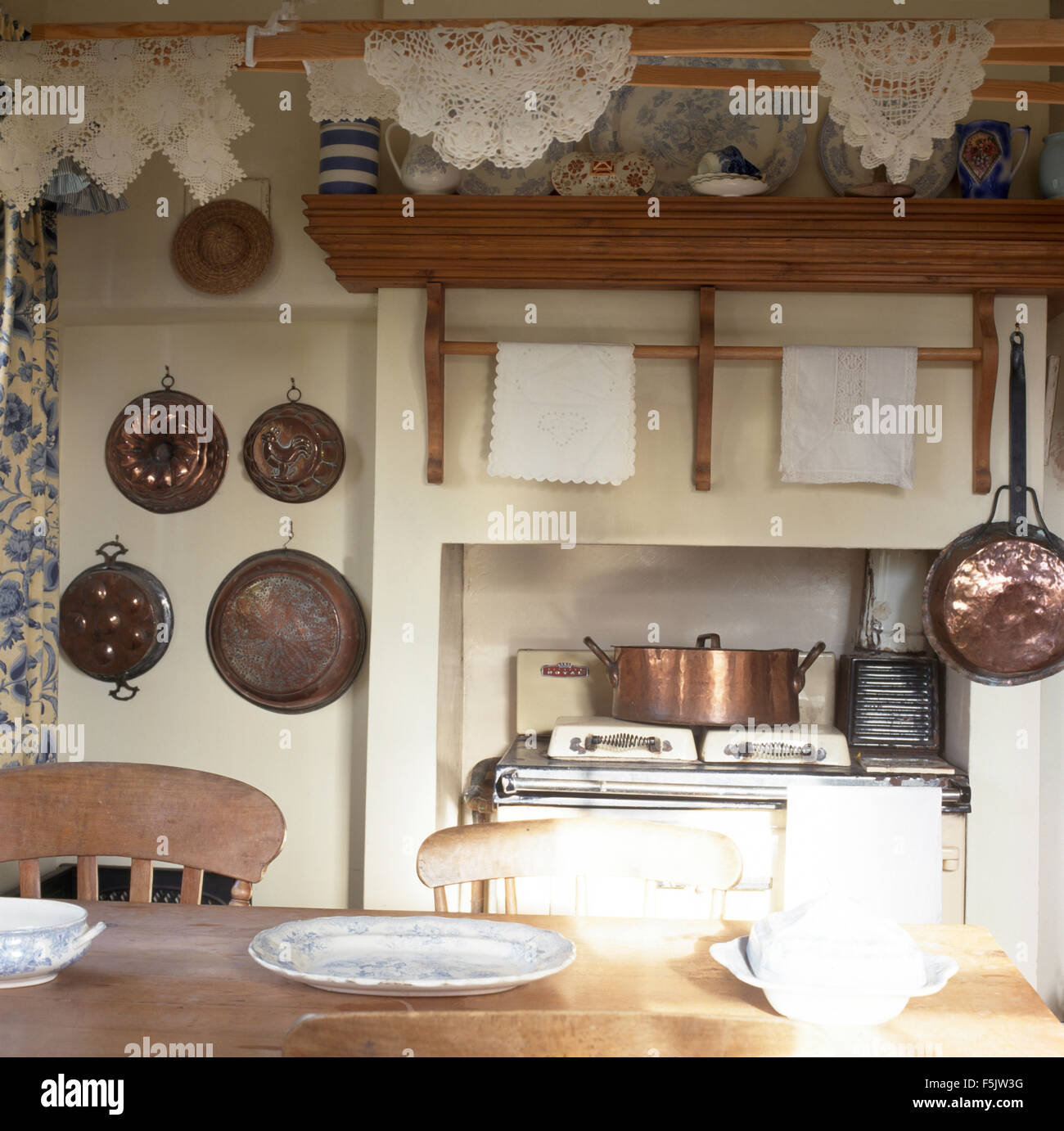Vintage copper pans on wall beside range oven in cottage kitchen with