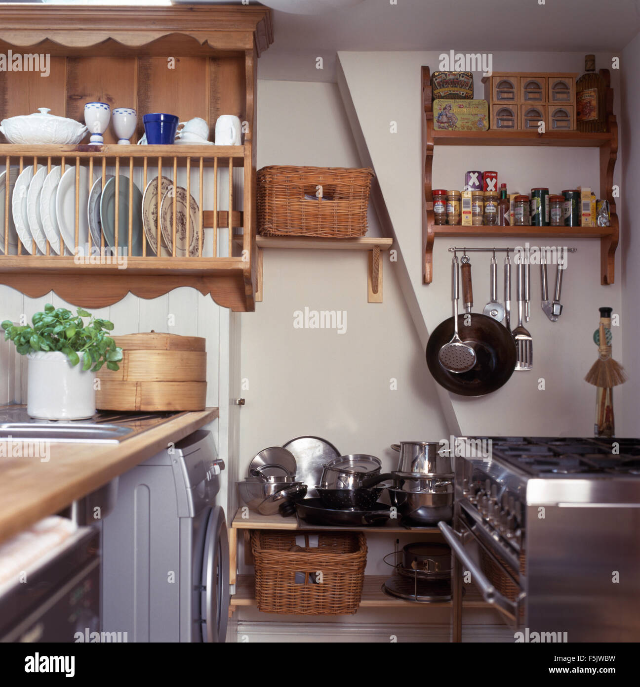 Pine plate rack above worktop in a cottage kitchen with stainless steel pans on rack below