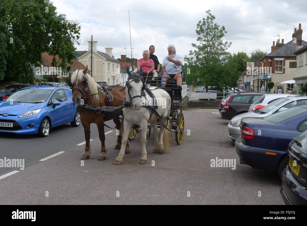 A two horse and carriage drives through the town of Stockbridge in Hampshire Stock Photo
