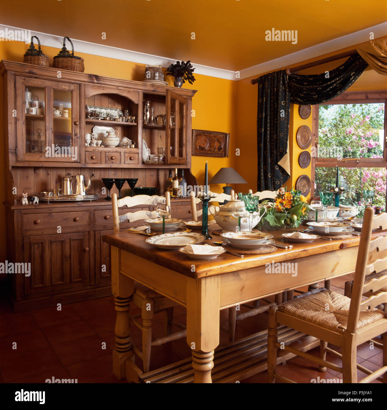 Ladder back chairs at pine table set for lunch in a yellow