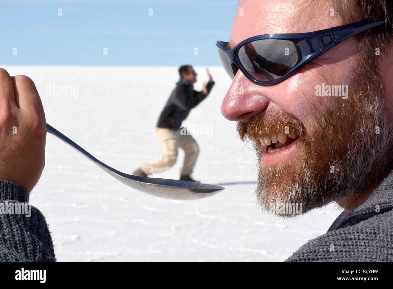Optical illusion, man holding a person on a spoon, salt lake Salar de Uyuni, Bolivia Stock Photo