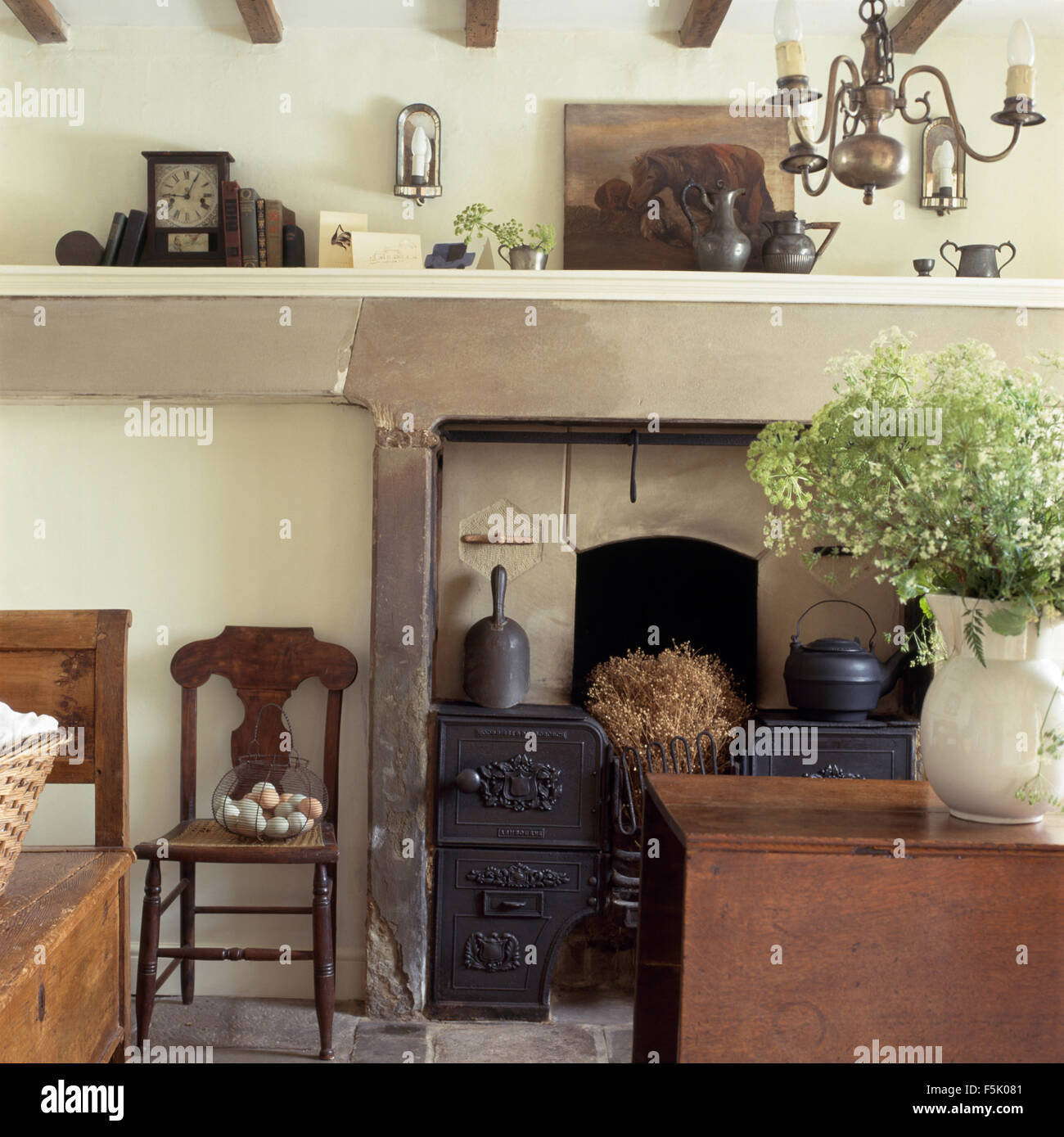Antique wooden chair beside fireplace with an original cast iron range oven in fireplace in a cottage dining room Stock Photo
