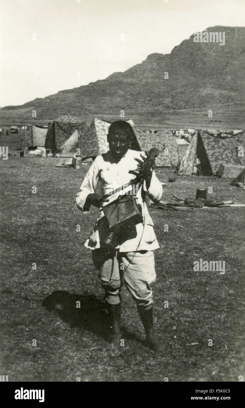 An African plays a stringed instrument in the camp Italian colonial Army , East Africa Stock Photo