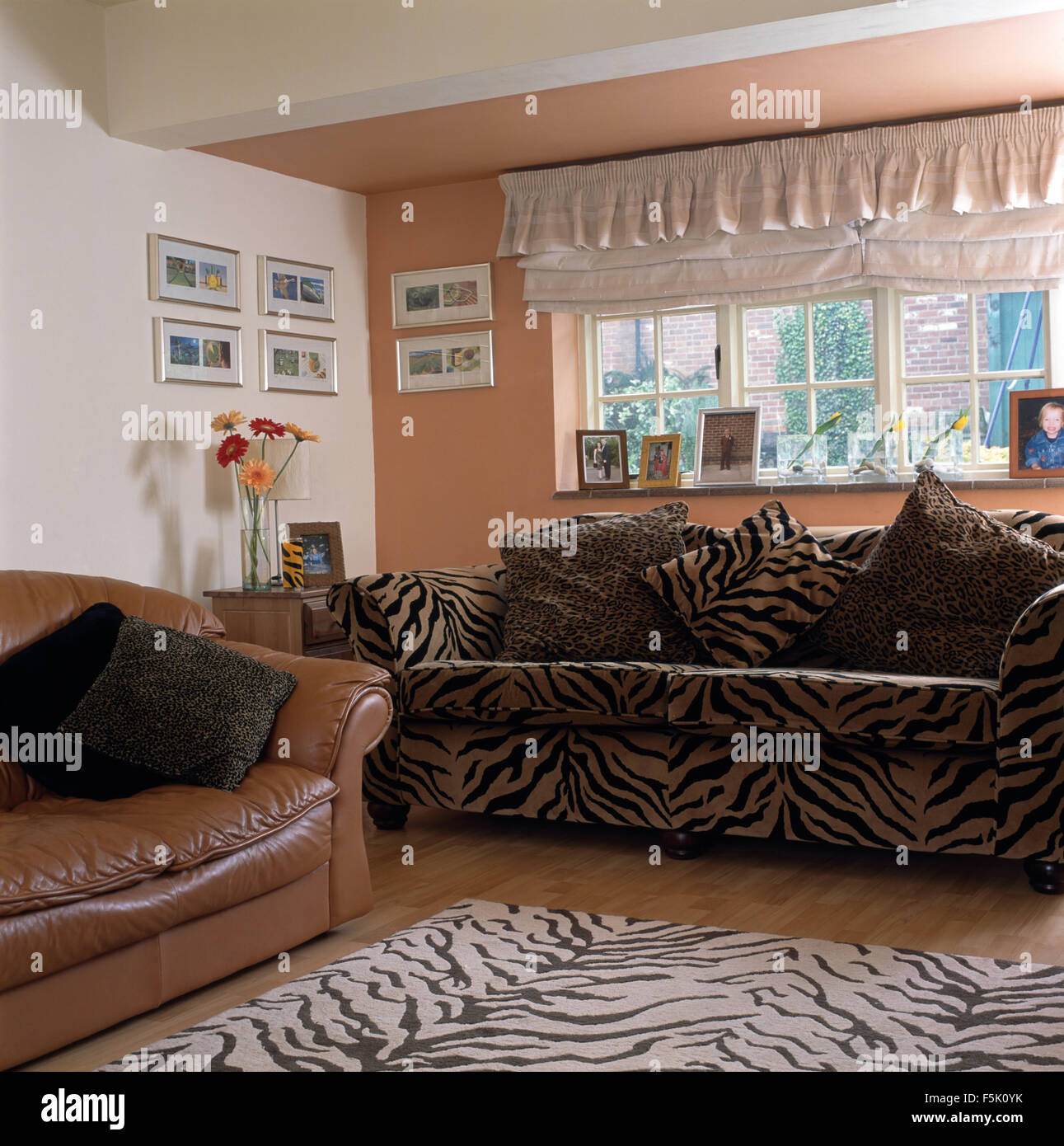 Frilled blind above tiger print sofa and matching rug in nineties living room with a tan leather sofa Stock Photo