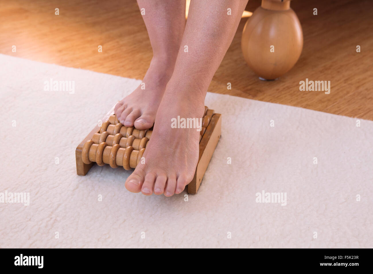 feet on wooden massage roller in bedroom Stock Photo