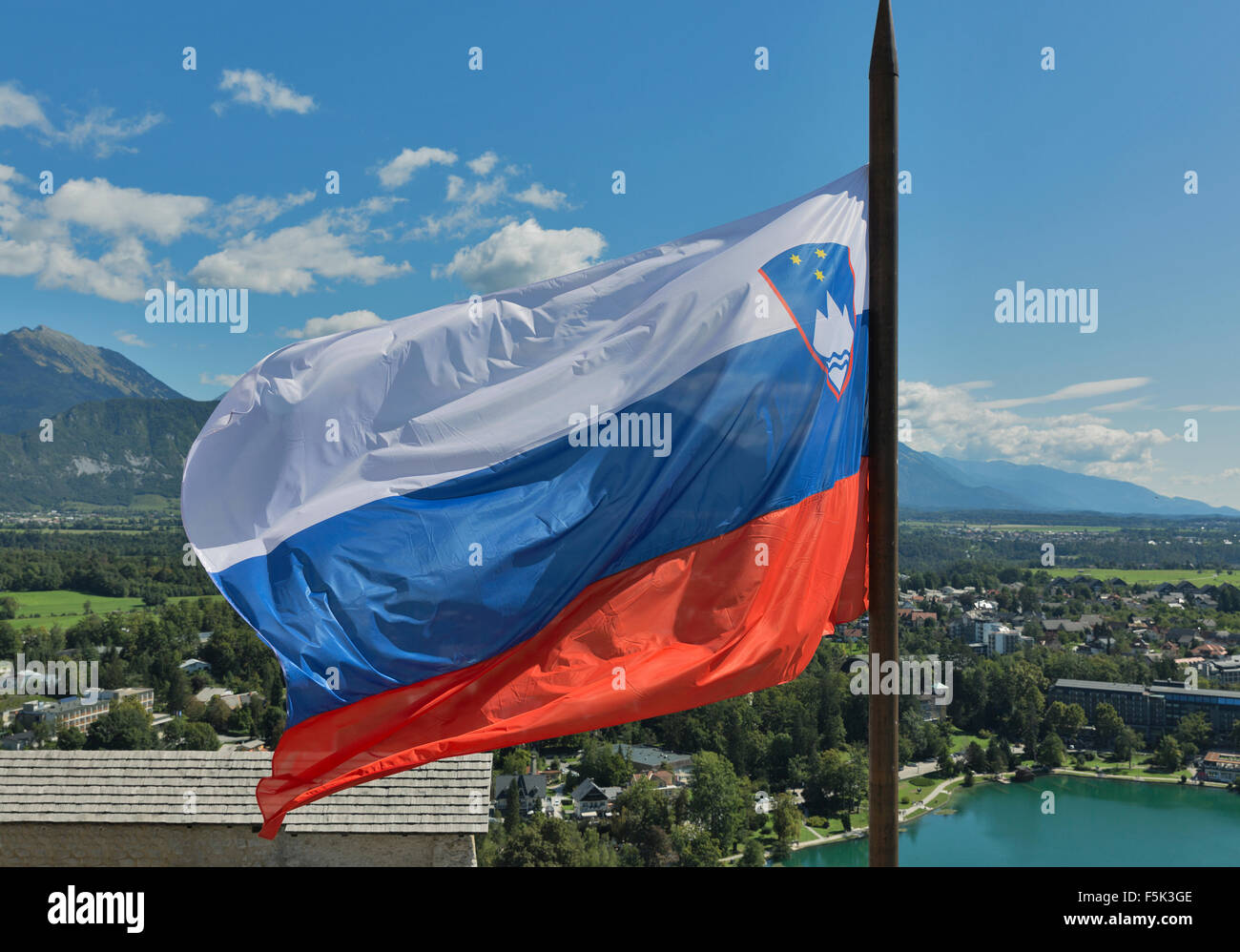 Slovenian national flag fluttering over Lake Bled and town Stock Photo