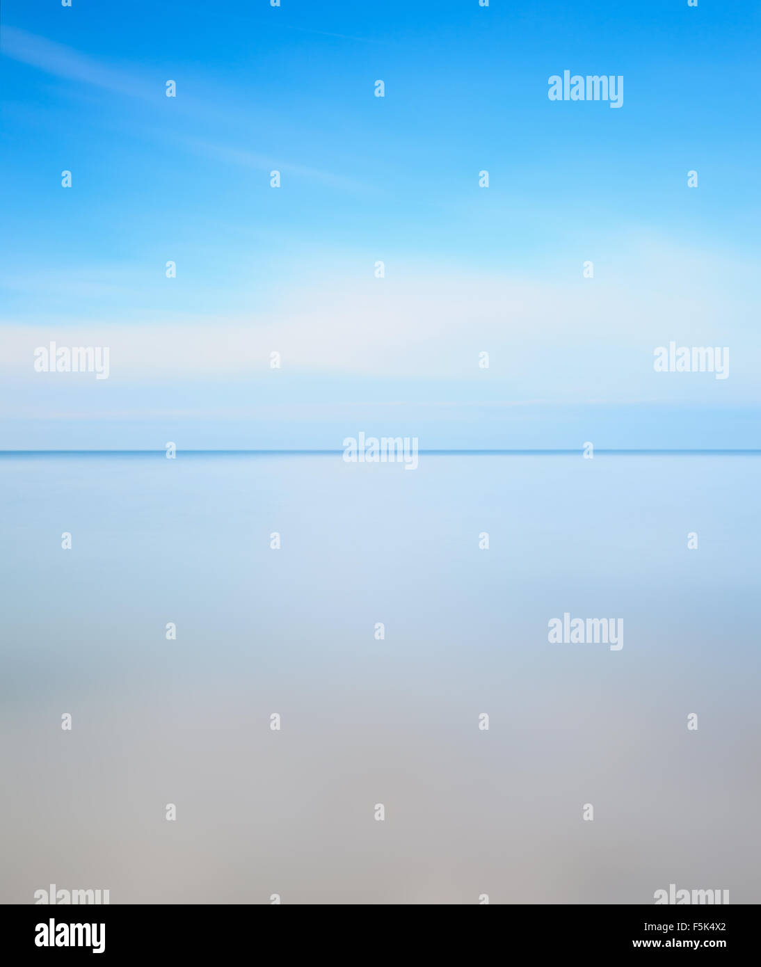 Horizon line, soft water sea and light cloudy blue sky. Long exposure photography over one minute. Stock Photo