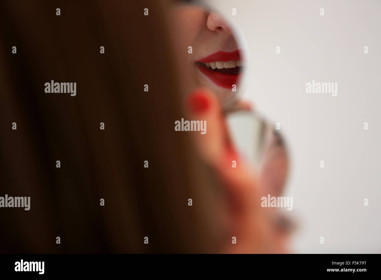 Young pretty girl applying red lipstick to her lips in Worthing, West Sussex, UK. Stock Photo