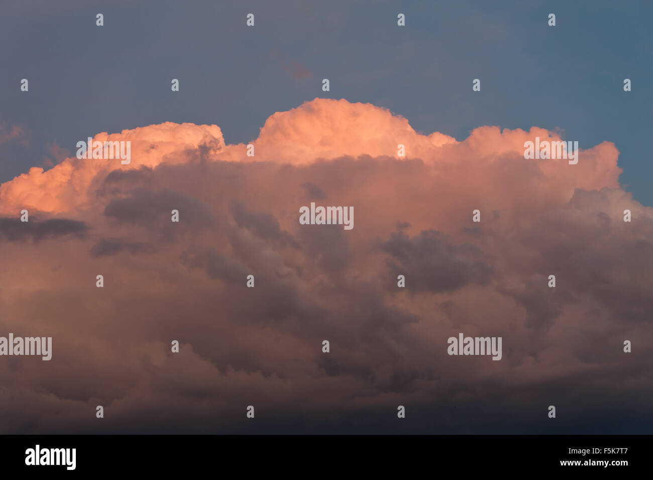 Dark brooding cloudscape, orange colors sunlight on large cumulus clouds formation, cloudscape sunset weather in horizontal... Stock Photo