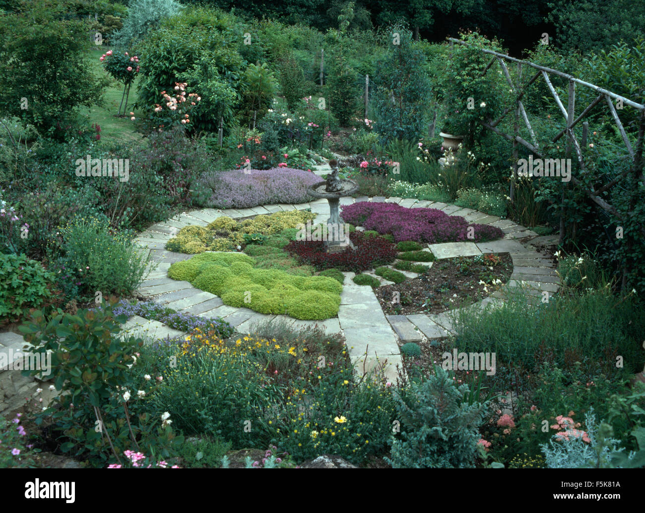 Herbs growing in a circular bed edged with a stone paved path in a large country garden in summer Stock Photo