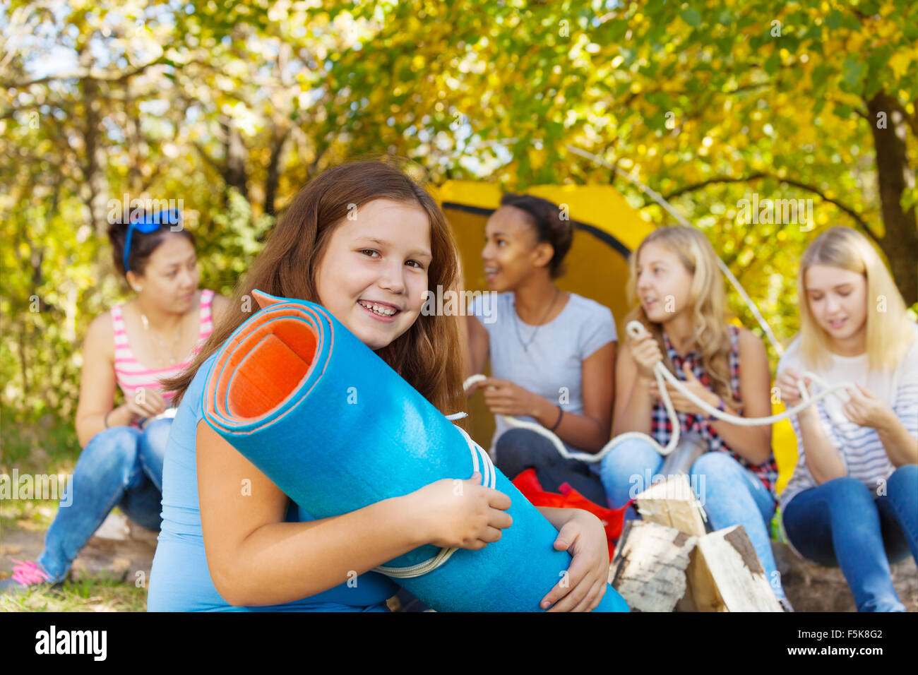 Happy girl holding blue rolled spandex mat Stock Photo