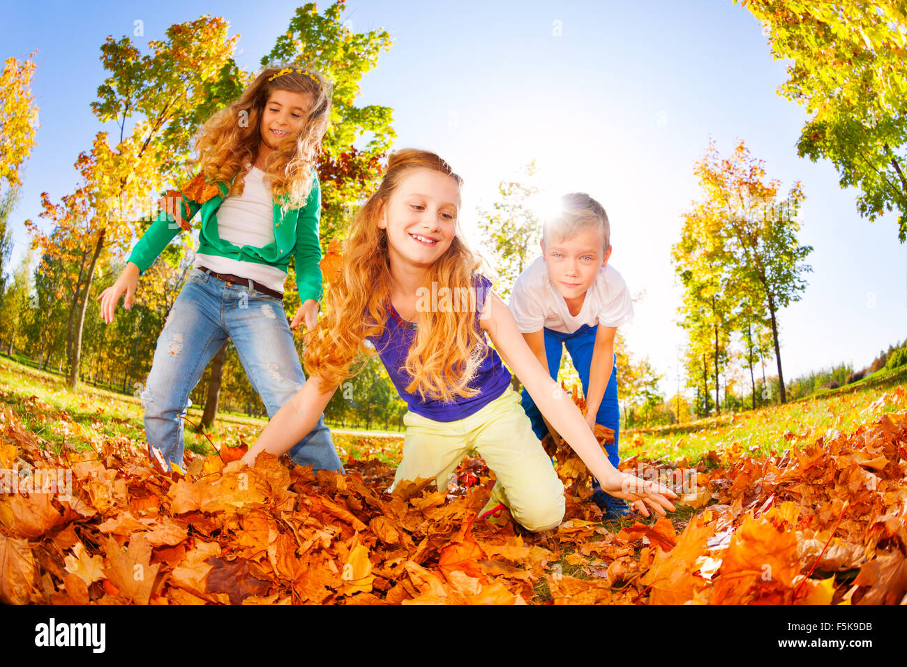 Happy friends playing red leaves in the forest Stock Photo - Alamy