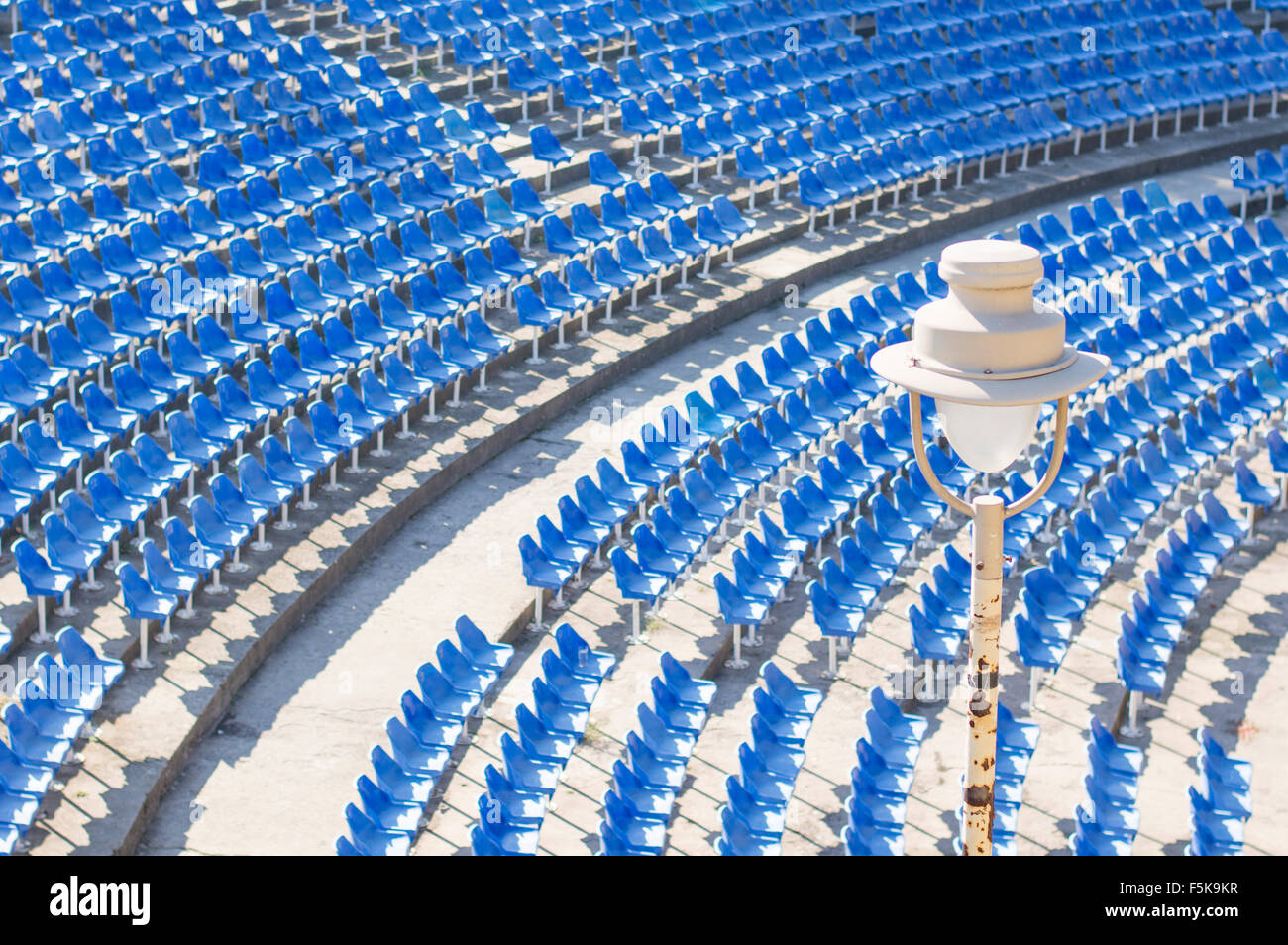 Light bulb in an empty amphitheater with blue chairs hall on daytime Stock Photo