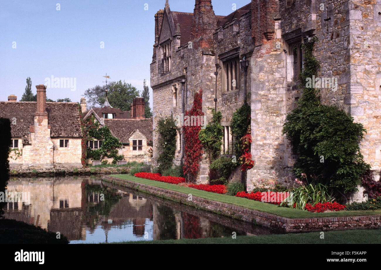 Exterior of a large, fortified country house with a moat and bright red salvias in a neat border Stock Photo