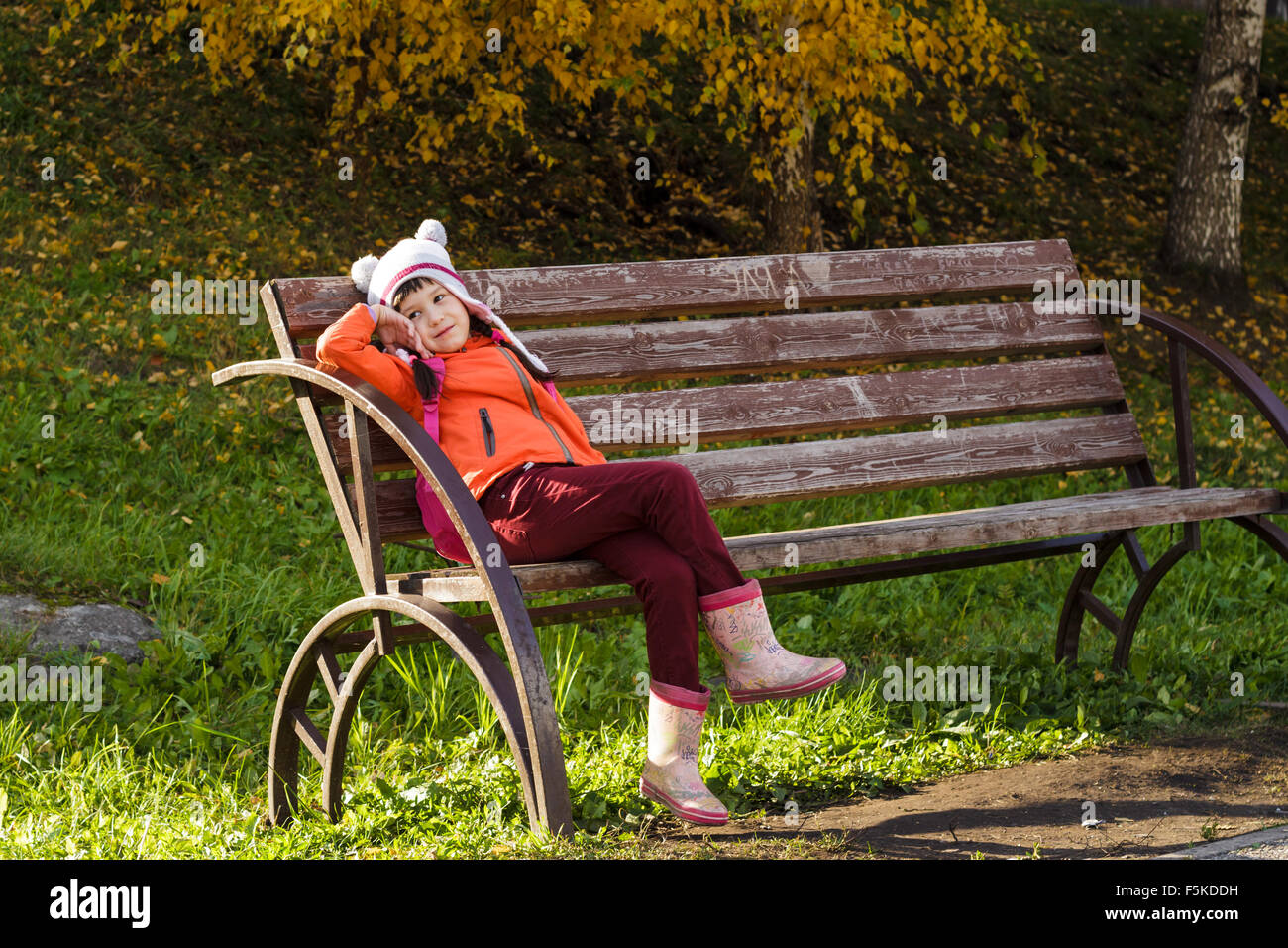 Little girl sitting on a bench in autumn Stock Photo - Alamy