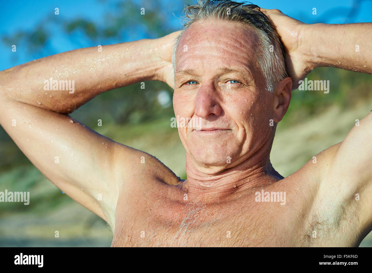 Portrait of a mature aged man after a swim in the ocean. Water droplets are running down his face,shoulders and arms. Stock Photo