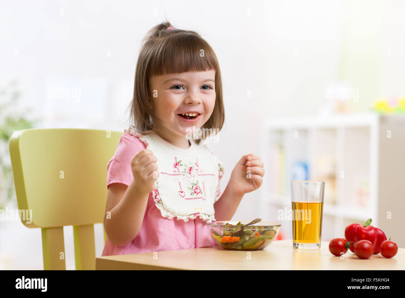 Toddler sitting at table food ready to eat in the nursery. Vegetarian salad and fresh vegetables for child lunch. Stock Photo
