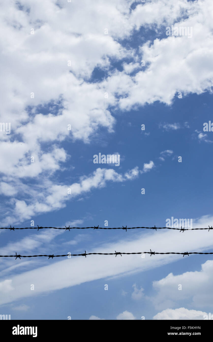 Barbed wire fence with blue sky and clouds in the background Stock ...