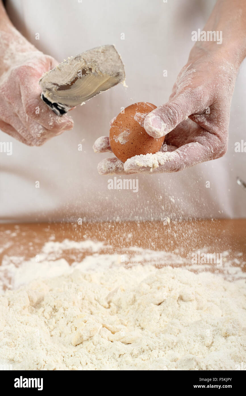 A baker cracking an egg into a pile of flour. Making Pastry Dough for