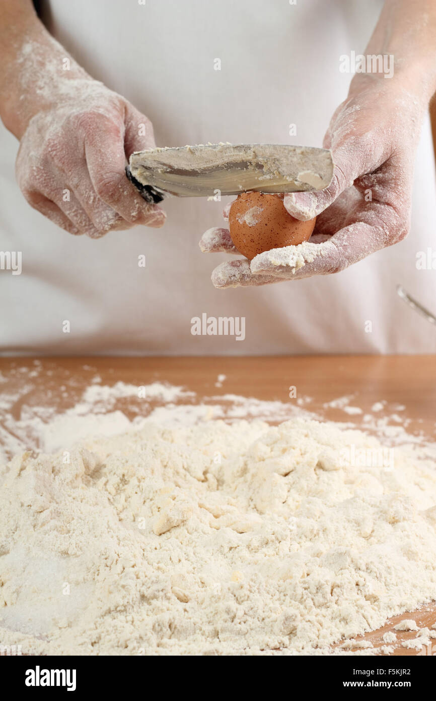A baker cracking an egg into a pile of flour. Making Pastry Dough for