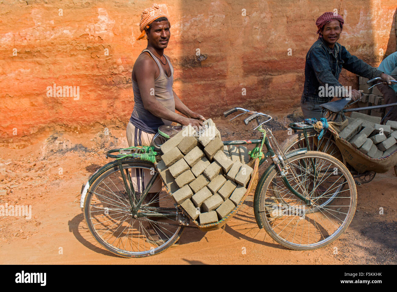 Worker is transporting a charge of raw unburnt bricks on a bicycle