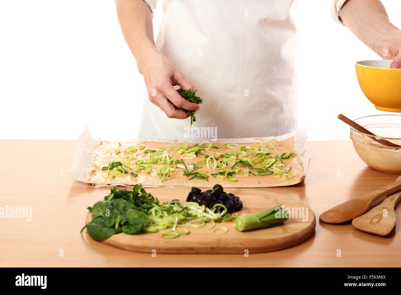 Spreading sliced spinach on dough. Making Pizza with Leek and Spinach. Series. Stock Photo