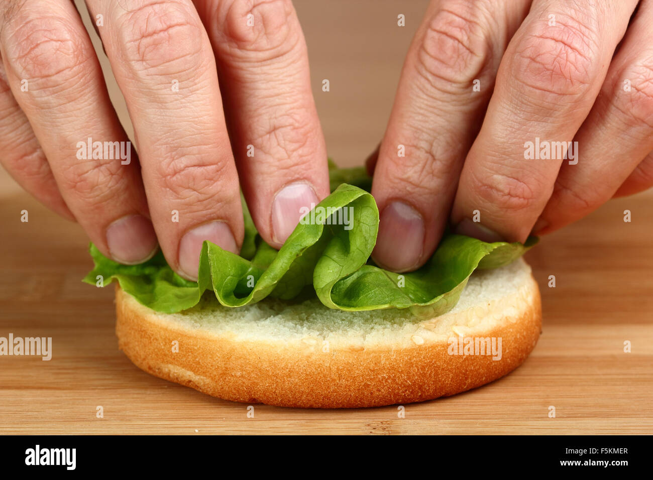Put Lettuce on bread roll. Making Hamburger. Macro. Series. 2/12 Stock
