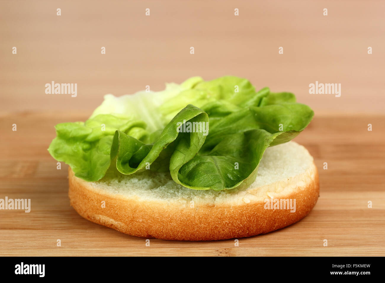 Put Lettuce on bread roll. Making Hamburger. Macro. Series. 3/12 Stock Photo 89558305 Alamy