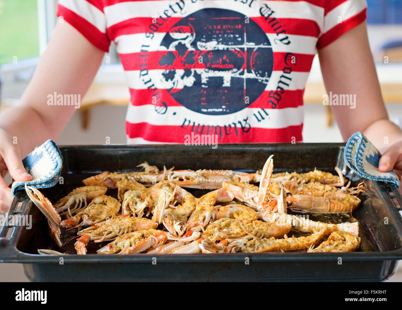 Sweden, Bohuslan, Woman holding hot baking pan with norway lobster (Nephrops norvegicus) Stock Photo