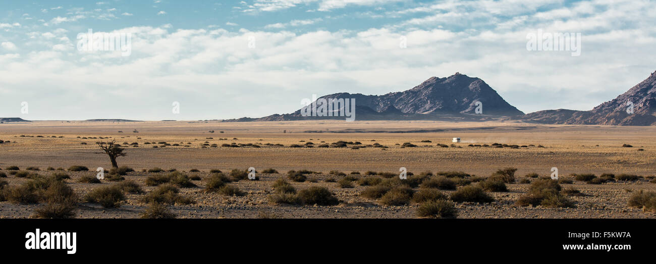 Lonely car in the Namib desert driving through the horizon Stock Photo