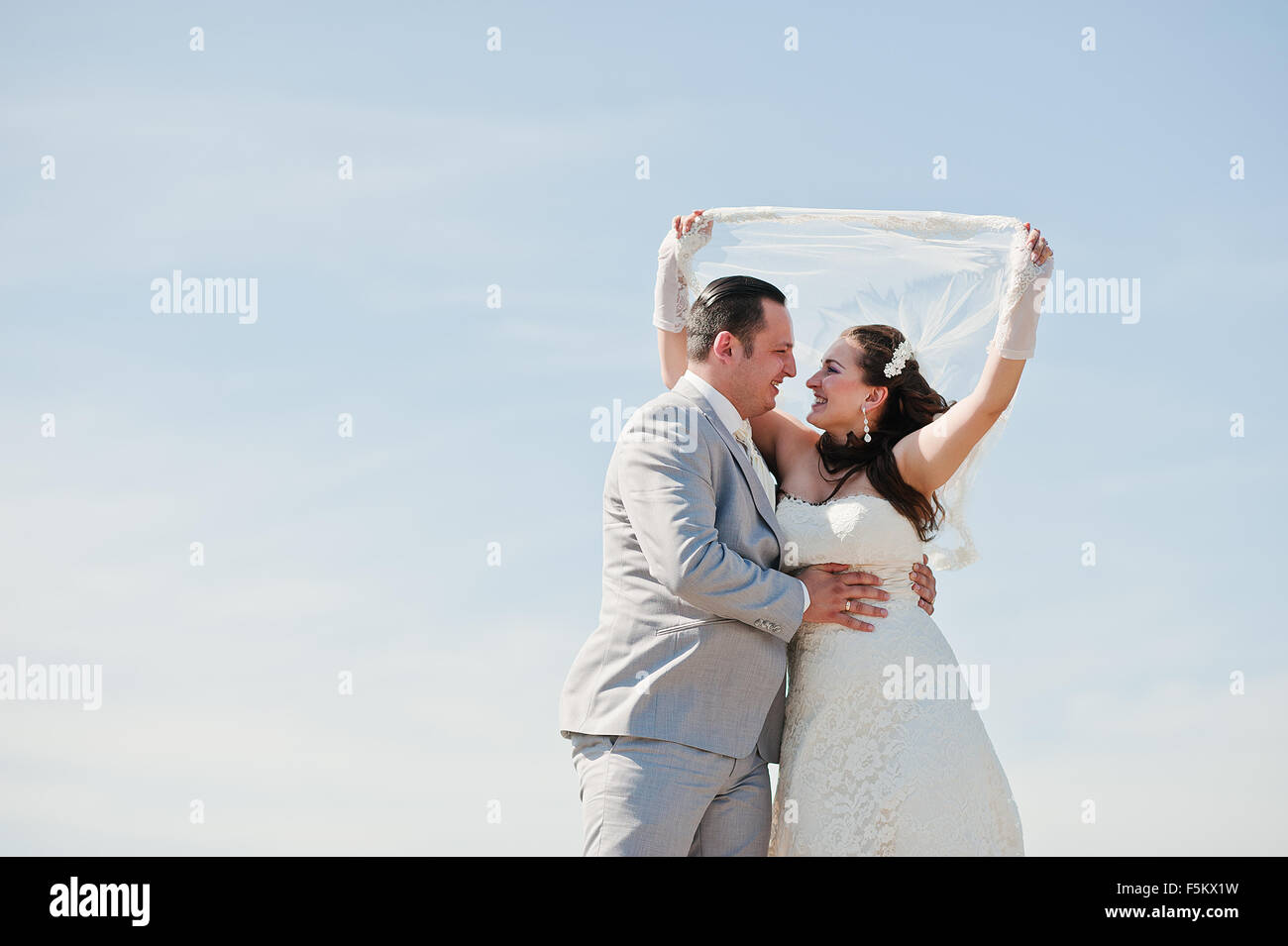 Young happy wedding couple background blue sky Stock Photo - Alamy