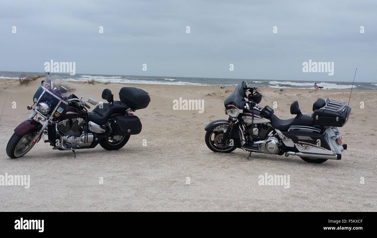 a pair of Motorcycles parked up on a sandy beach Stock Photo
